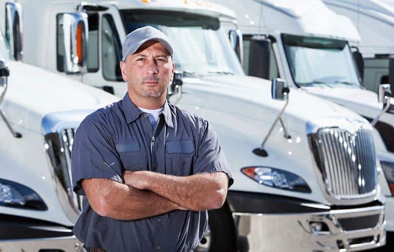 man standing in front of while truck in a garage