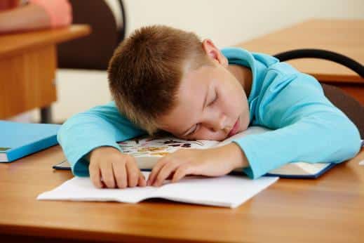 a baby boy sleeping on his desk in school