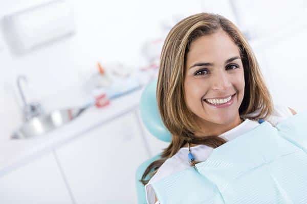 woman sitting on a dental unit while she is smiling