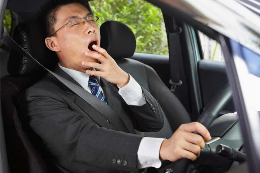 Asian man feeling tired while driving